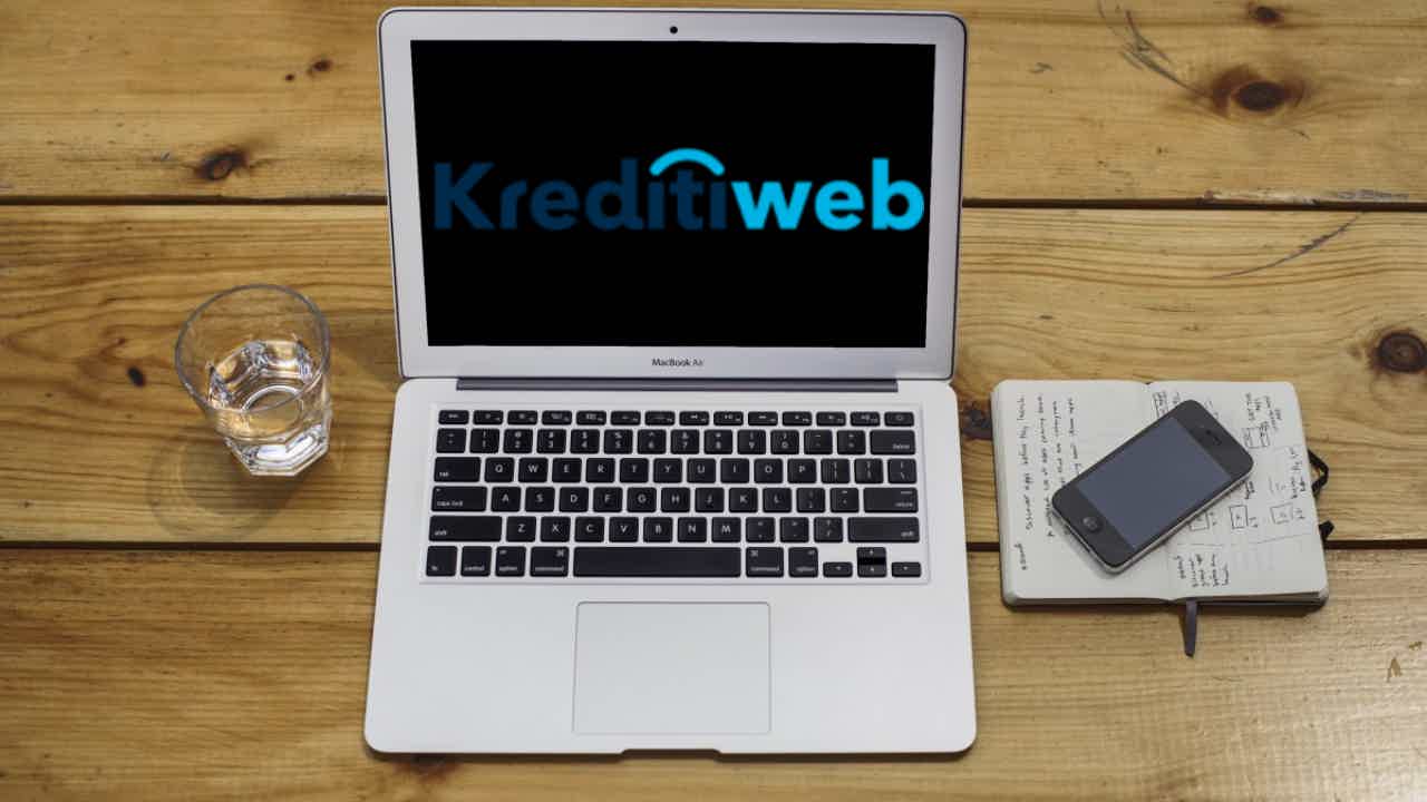 Laptop sobre uma mesa com o logo da Kreditiweb na tela. Fonte: Senhor Finanças / Kreditiweb.