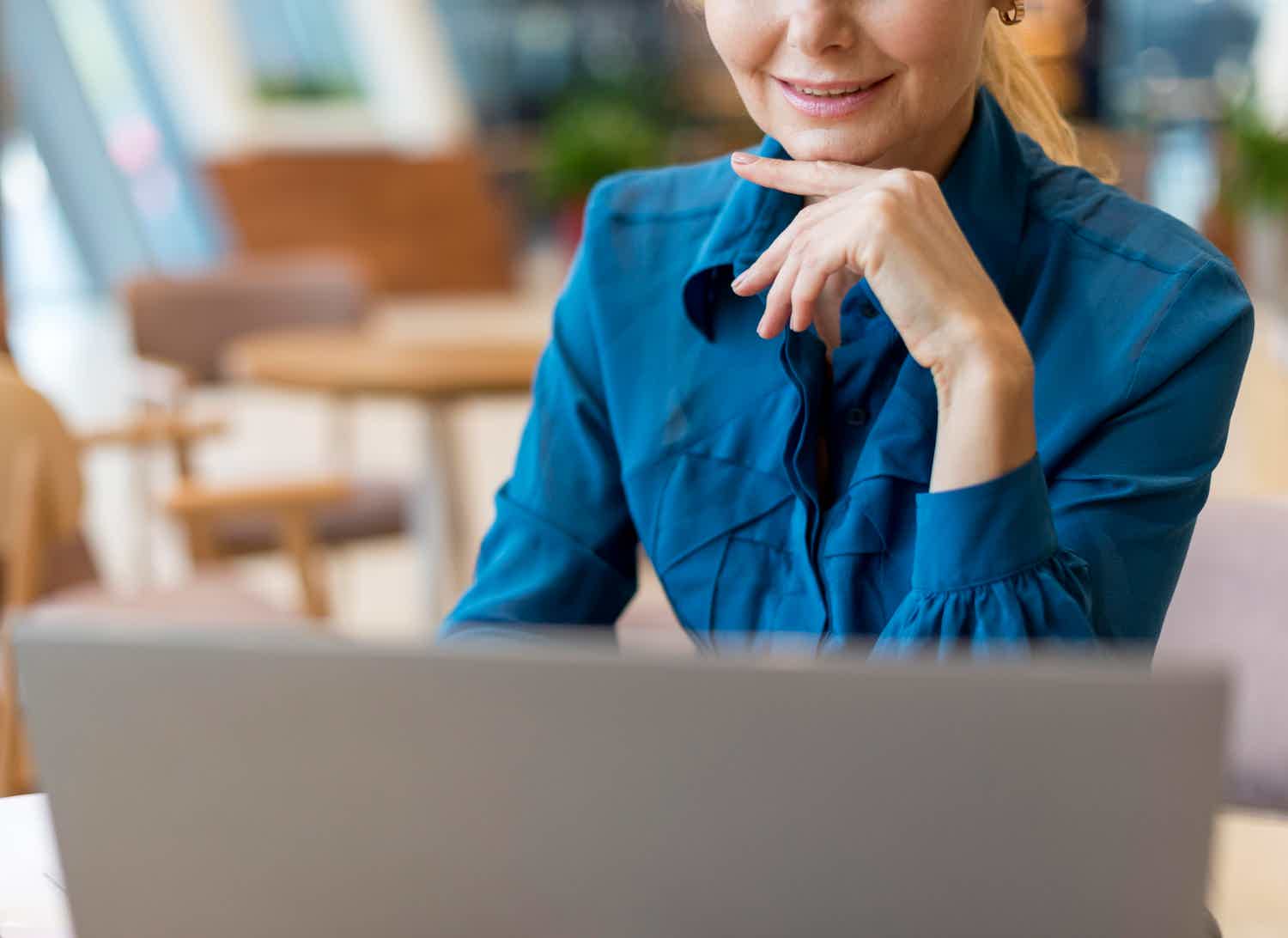 Mulher loira de camisa azul usando o notebook