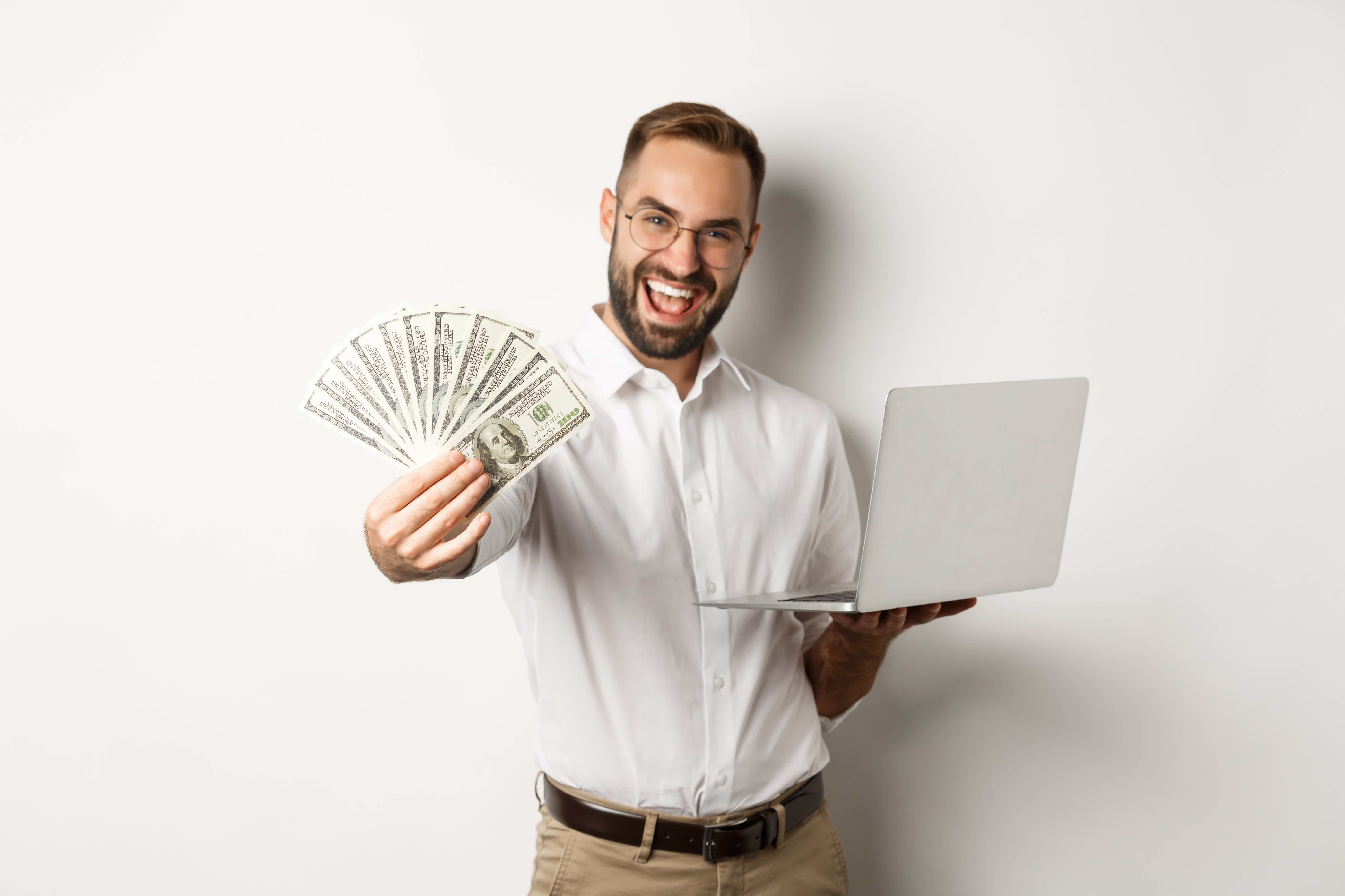 Homem com computador e dinheiro na mão