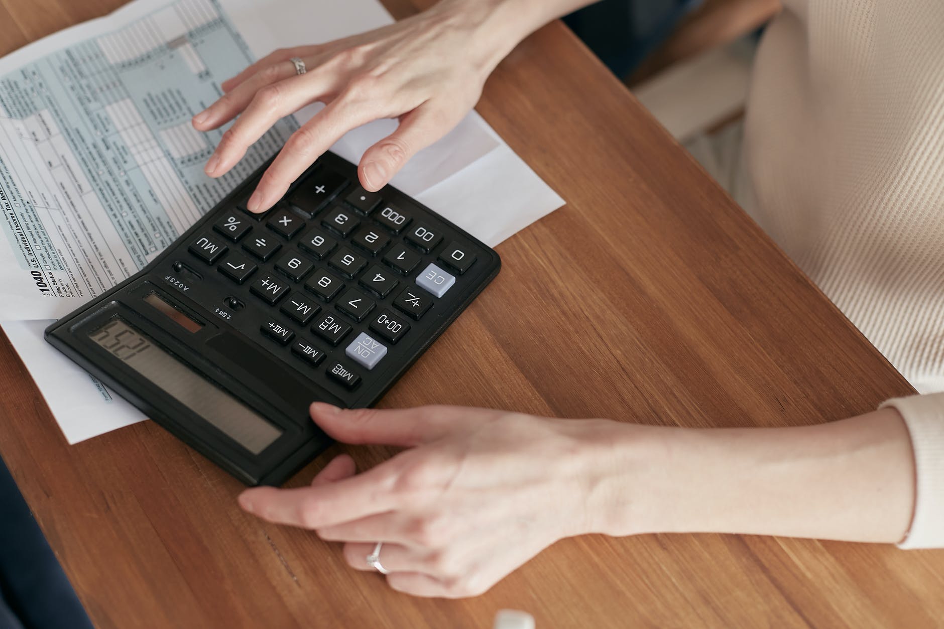 Pessoa usando calculadora com papéis em cima da mesa