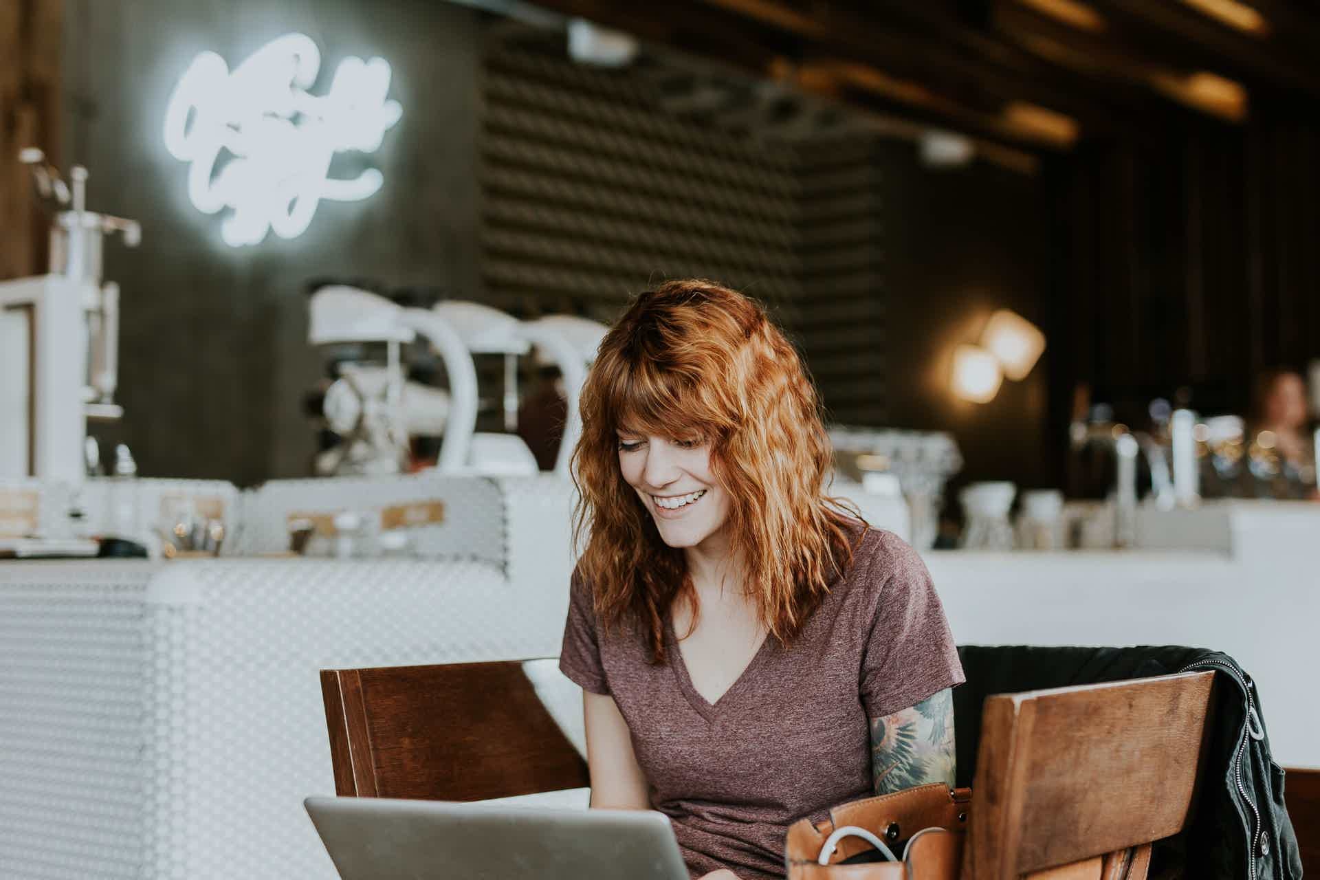 woman smiling and typing on a laptop