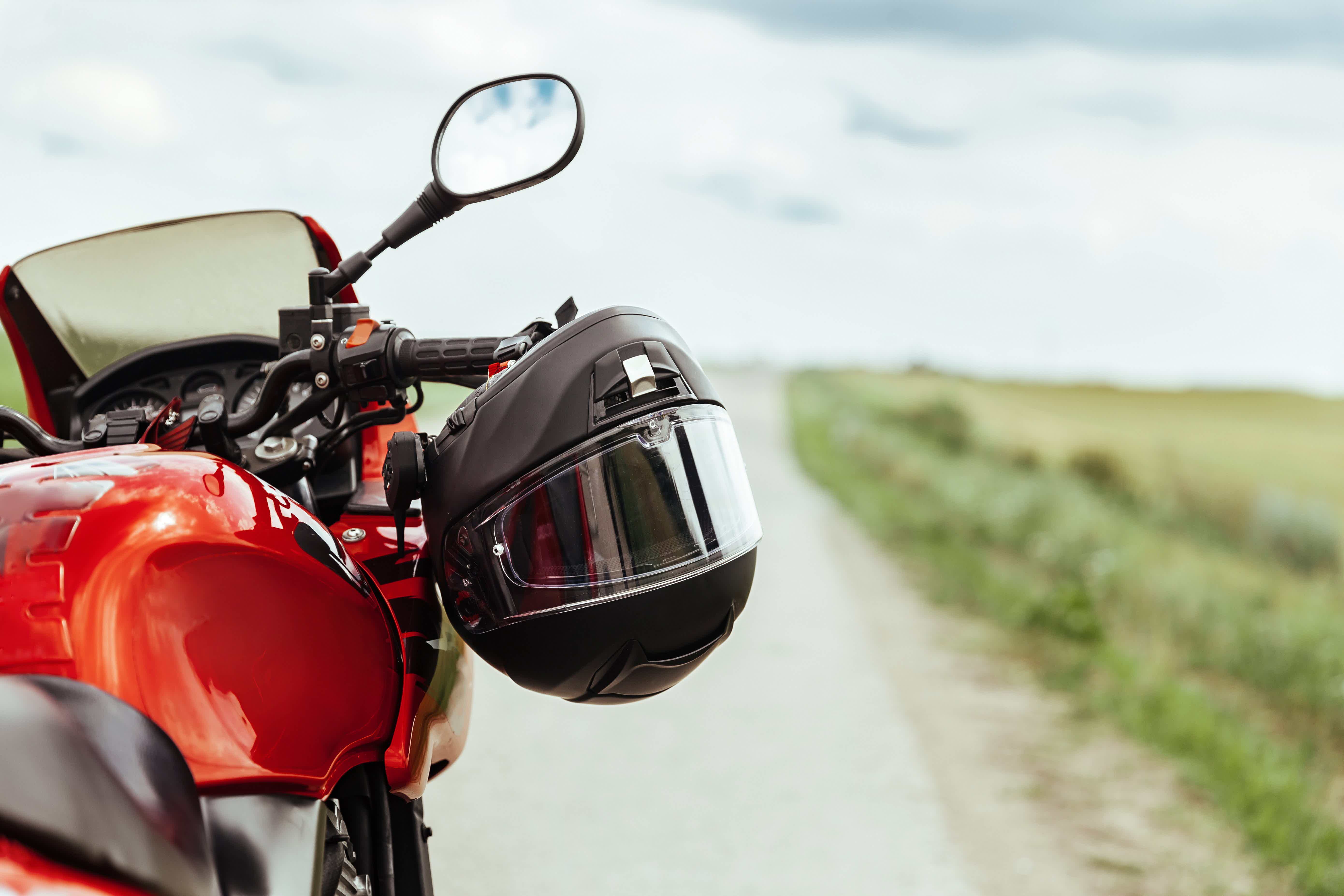 moto vermelha na estrada junto com capacete