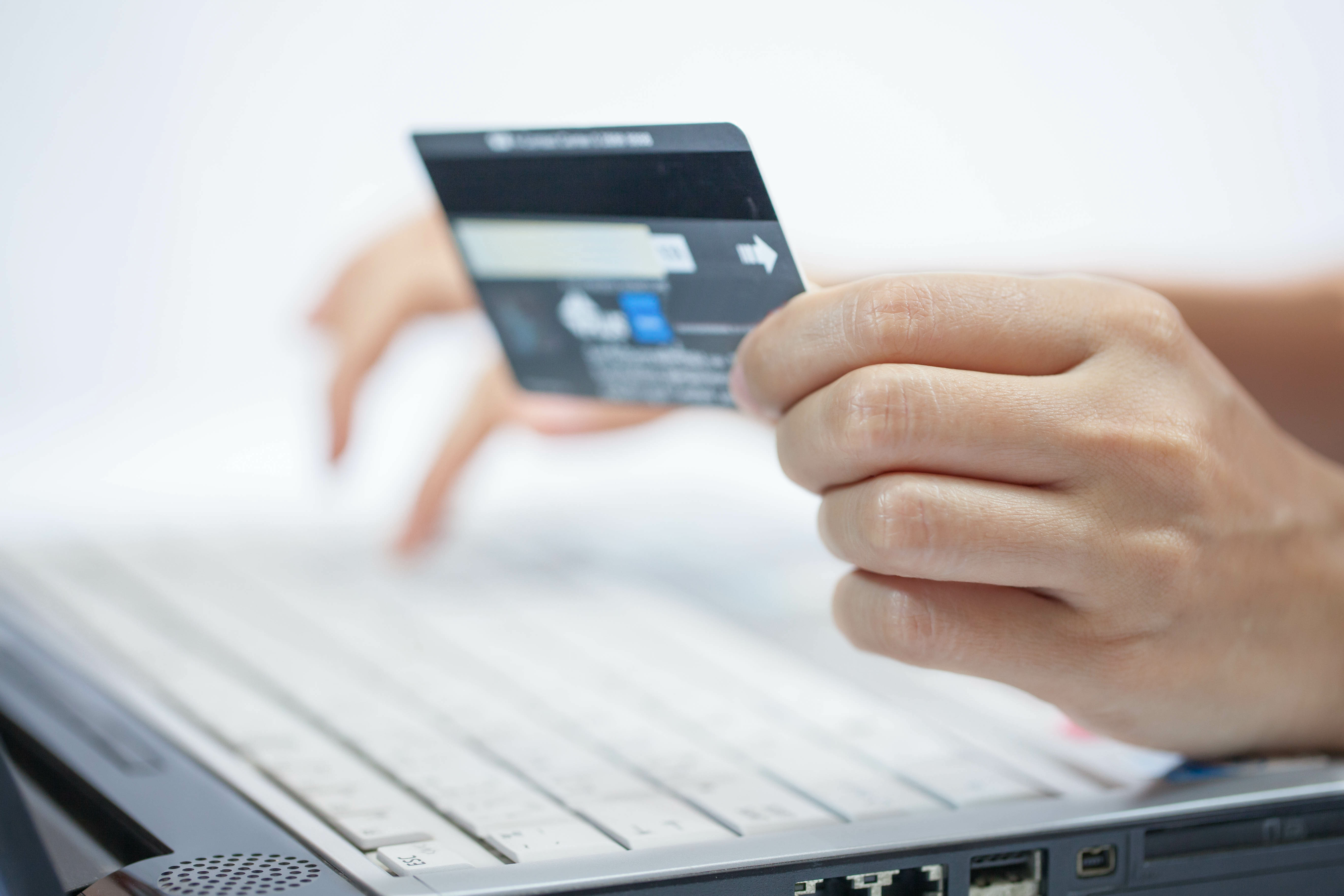 zoom of a person typing on a laptop and holding a credit card