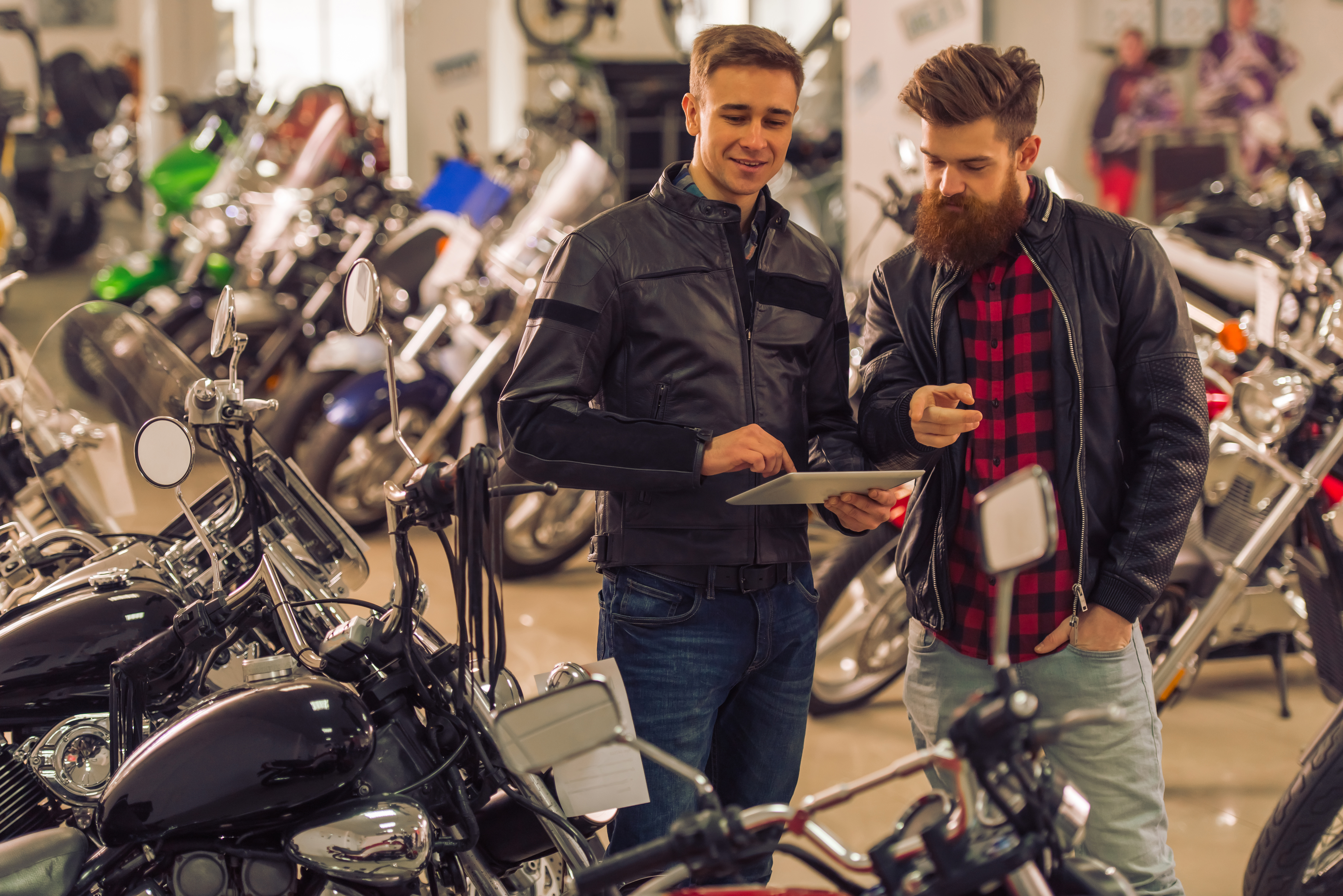 Homens olhando tablet em local com motos