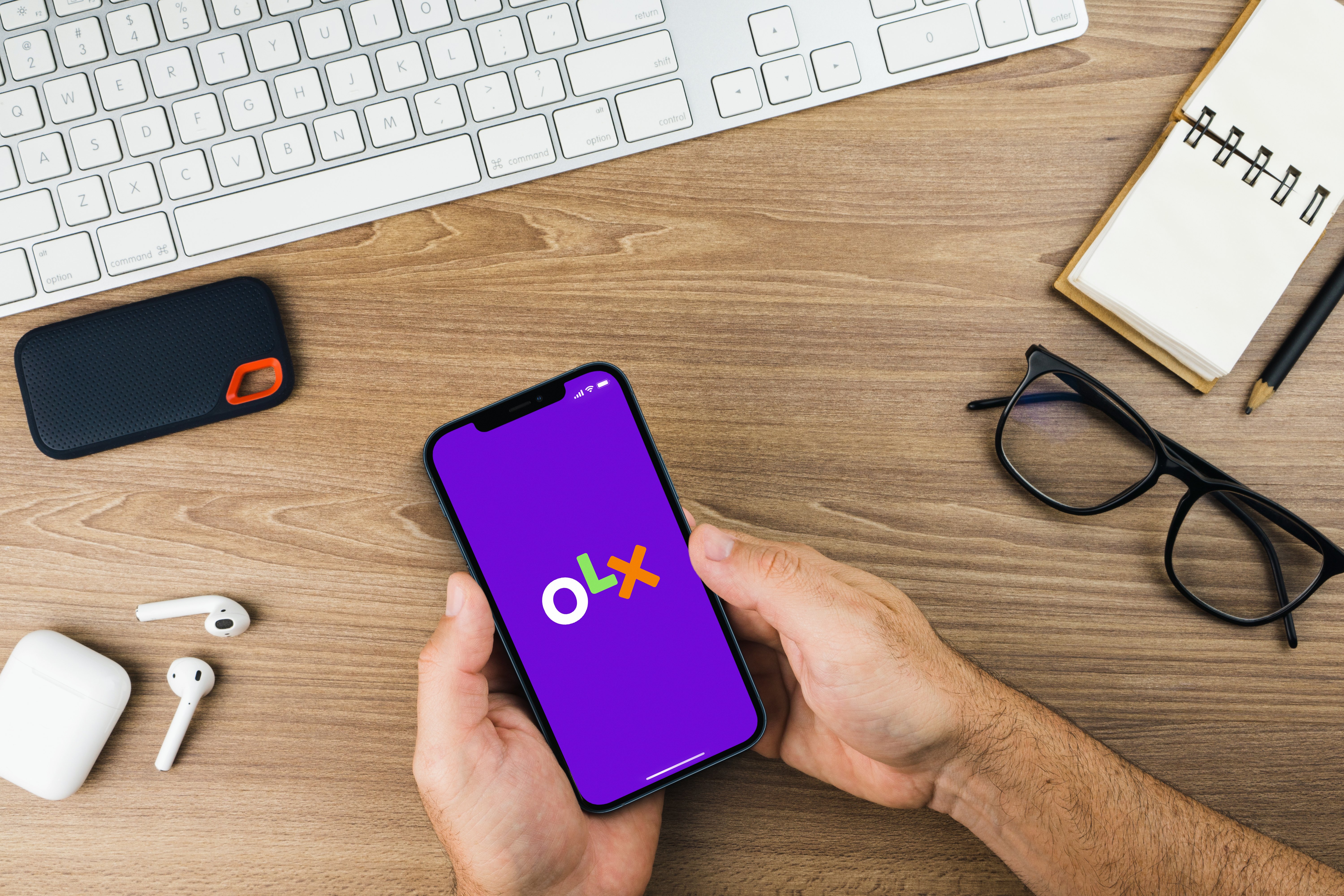 Pessoa segurando celular com app da OLX
