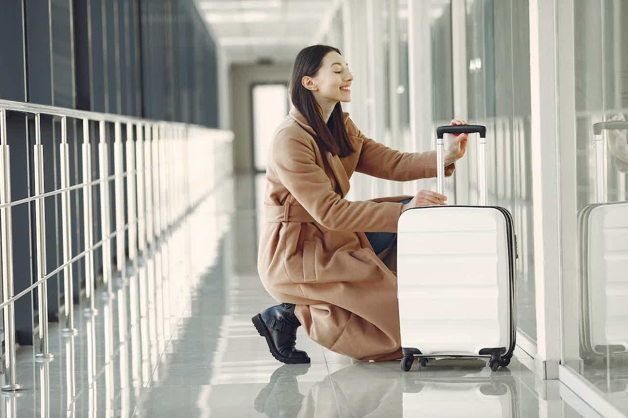 Mulher abaixada conferindo sua bagagem no corredor de um aeroporto