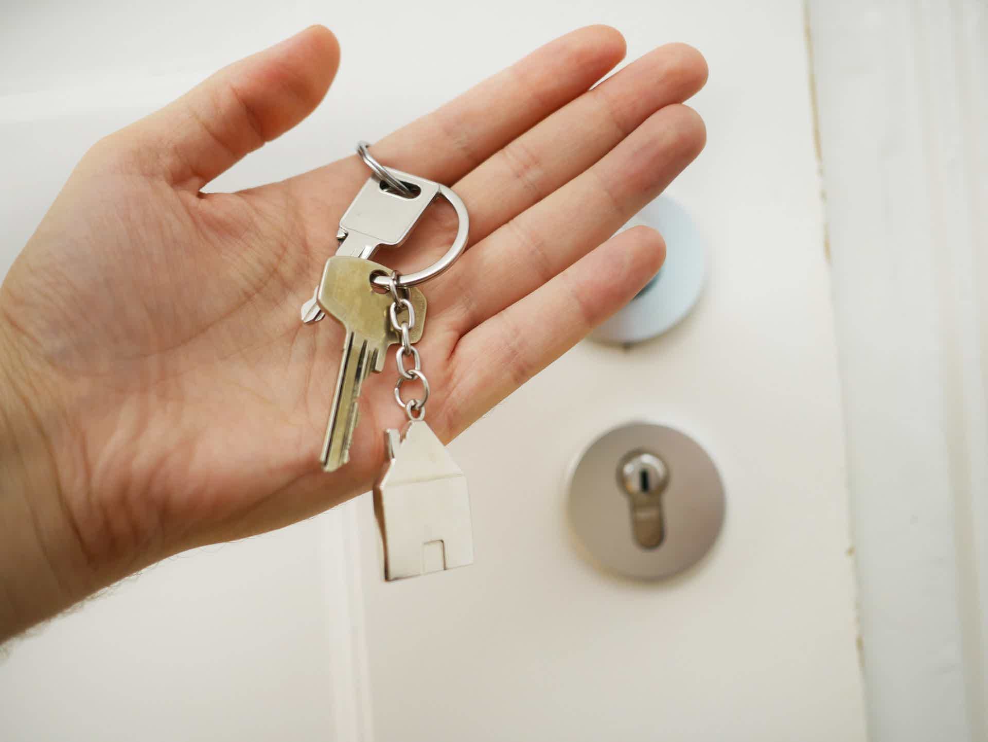 zoom of a hand holding a key with a house keychain