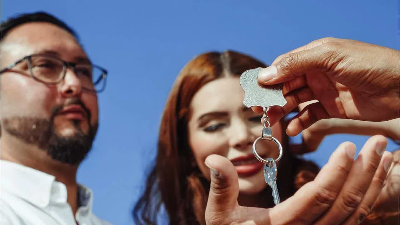 Mão entregando chave para casal