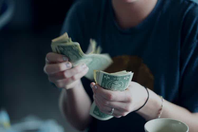 black background with two hands holding money bills