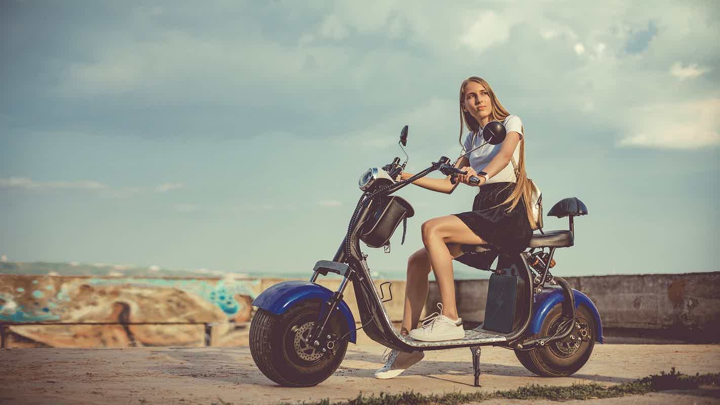 mulher parada com scooter estacionada