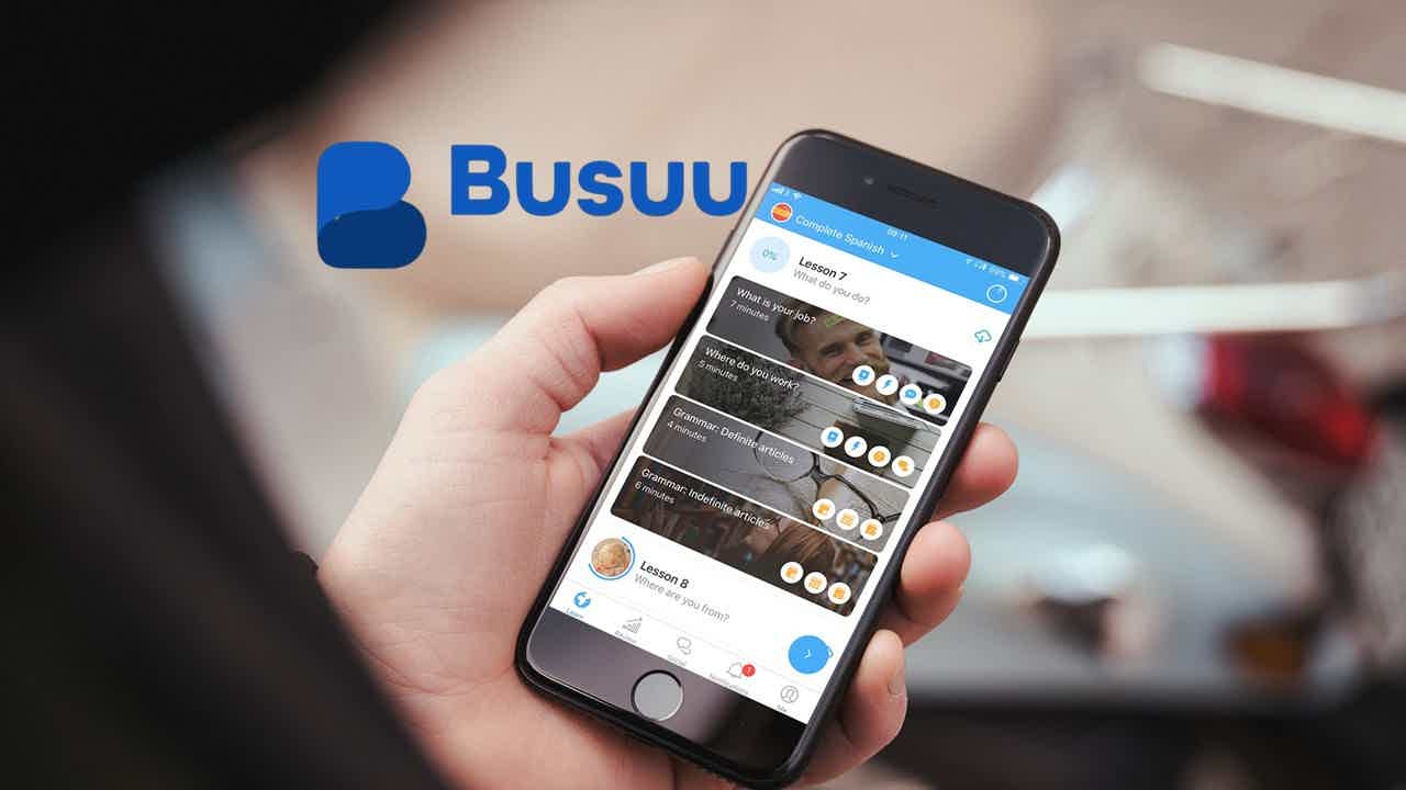 Mão segurando celular com app Busuu aberto