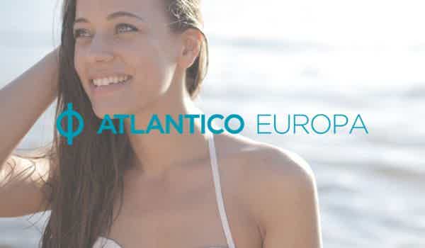 À frente, logo do banco Atlantico Europa na cor verde claro e, ao fundo uma mulher olha para o horizonte enquanto coloca uma mão sobre os cabelos e sorri.