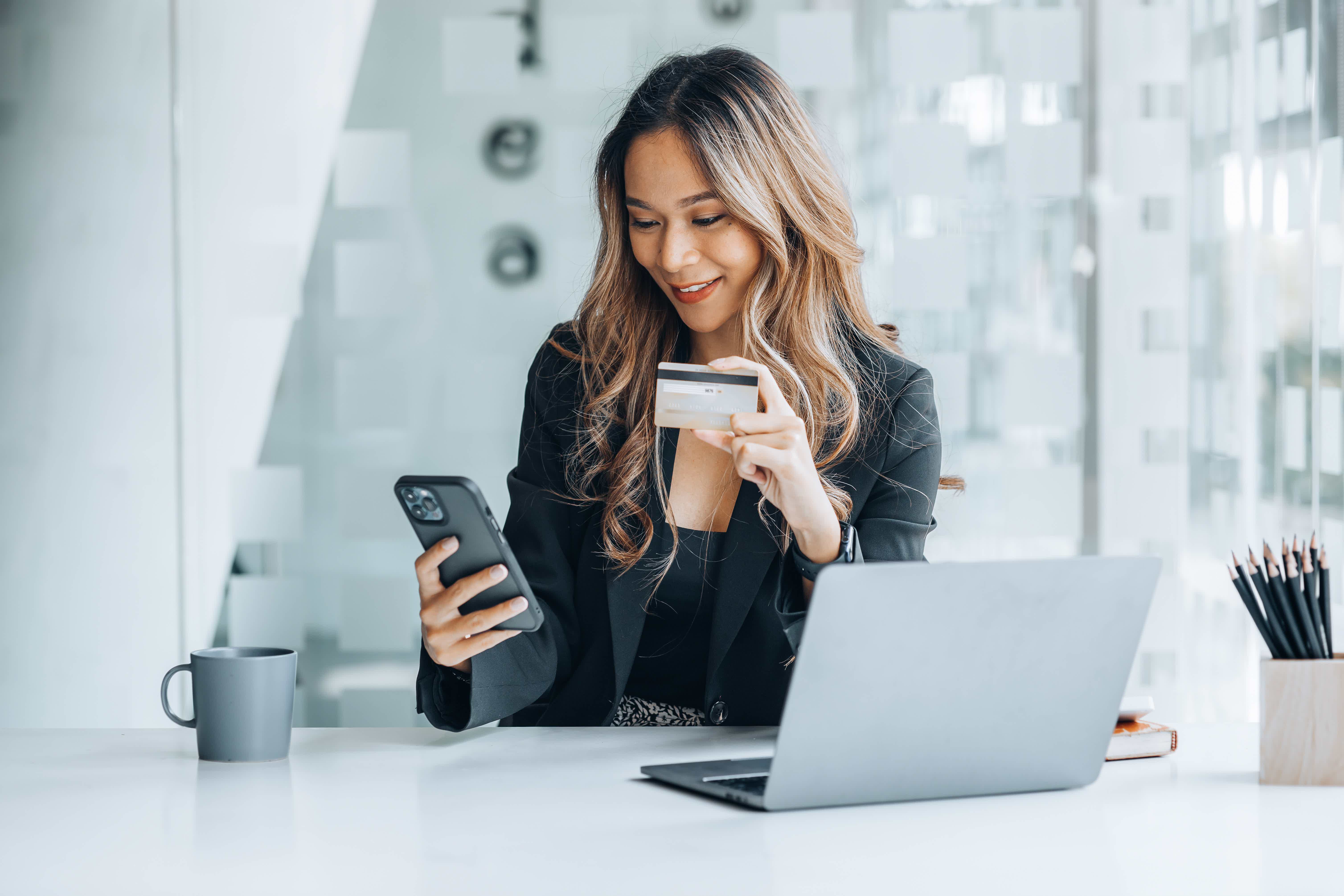 woman holding a credit card, she uses a credit card to pay for goods and services online