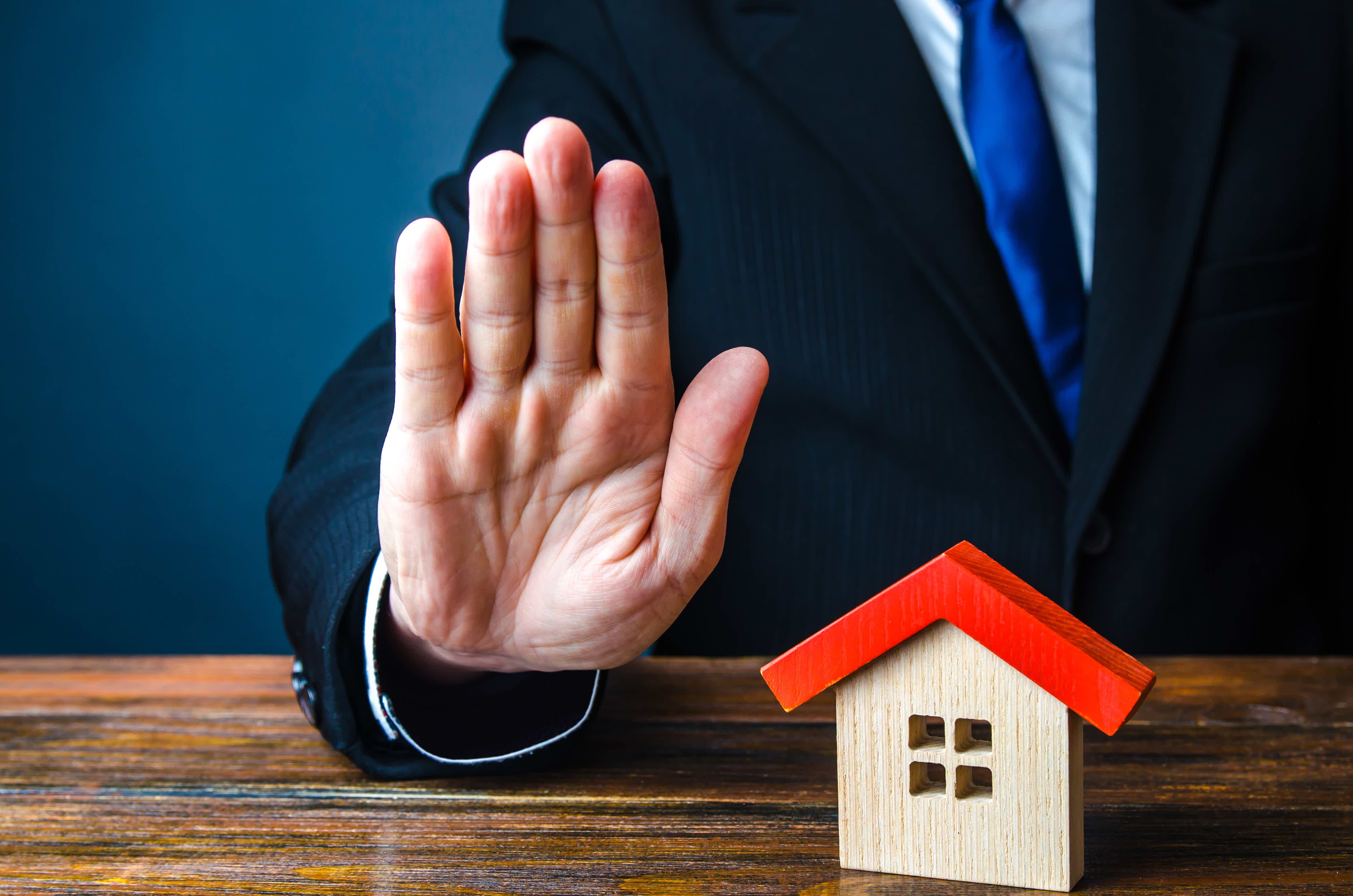 zoom of a hand standing beside a house miniature