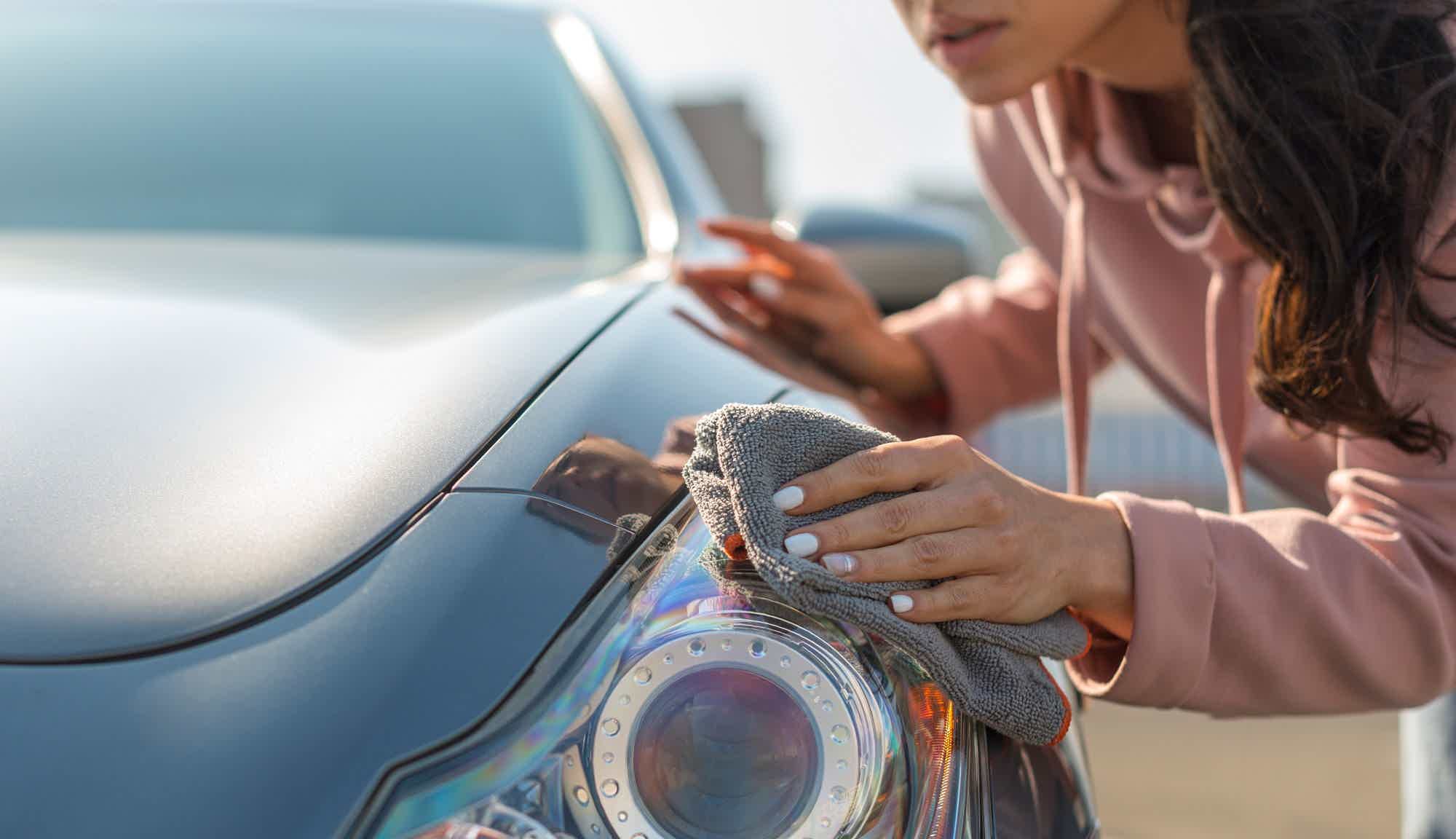 mulher limpando farol dianteiro do carro