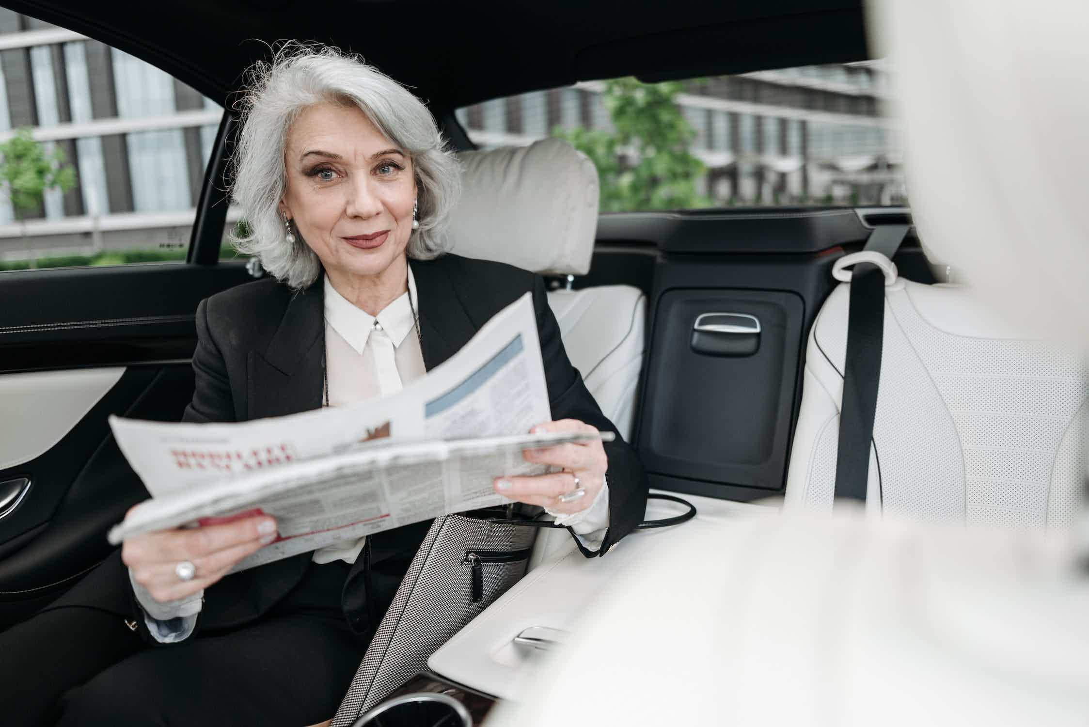 Mulher sentada dentro do carro vendo jornal