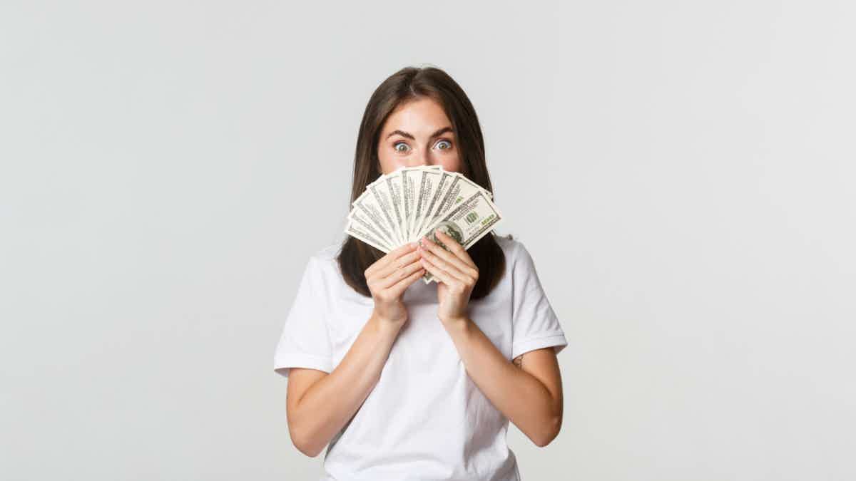 excited woman holding money in her hands from personal loans